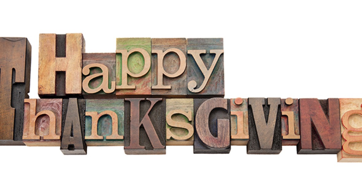 a series of wooden print blocks with letters of different sizes and colors spells out Happy Thanksgiving