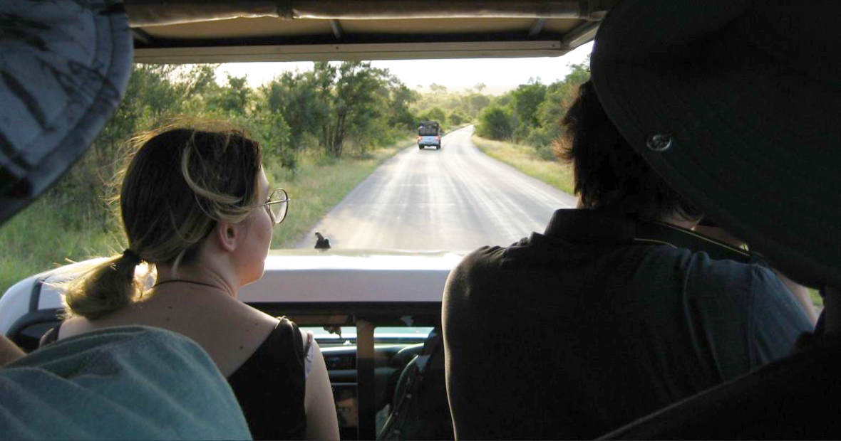 Looking out the front window of a jeep on a game drive, with a young woman sitting in the front seat.