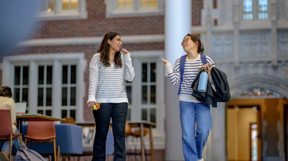 Two friends in the lobby of a building on campus.