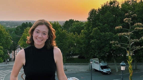 a woman smiles for a photo in front of a sunset