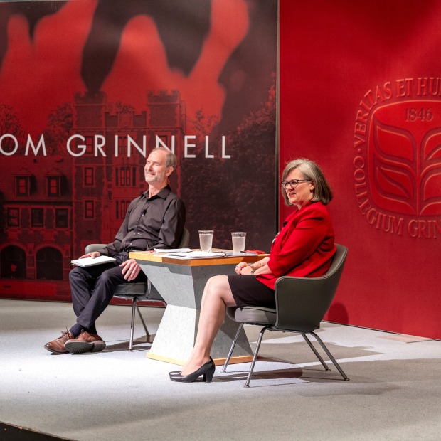 President Anne F. Harris and Board of Trustees’ Chair Michael Kahn ’74 on stage with backdrop of red Grinnell College logo and View from Grinnell sign