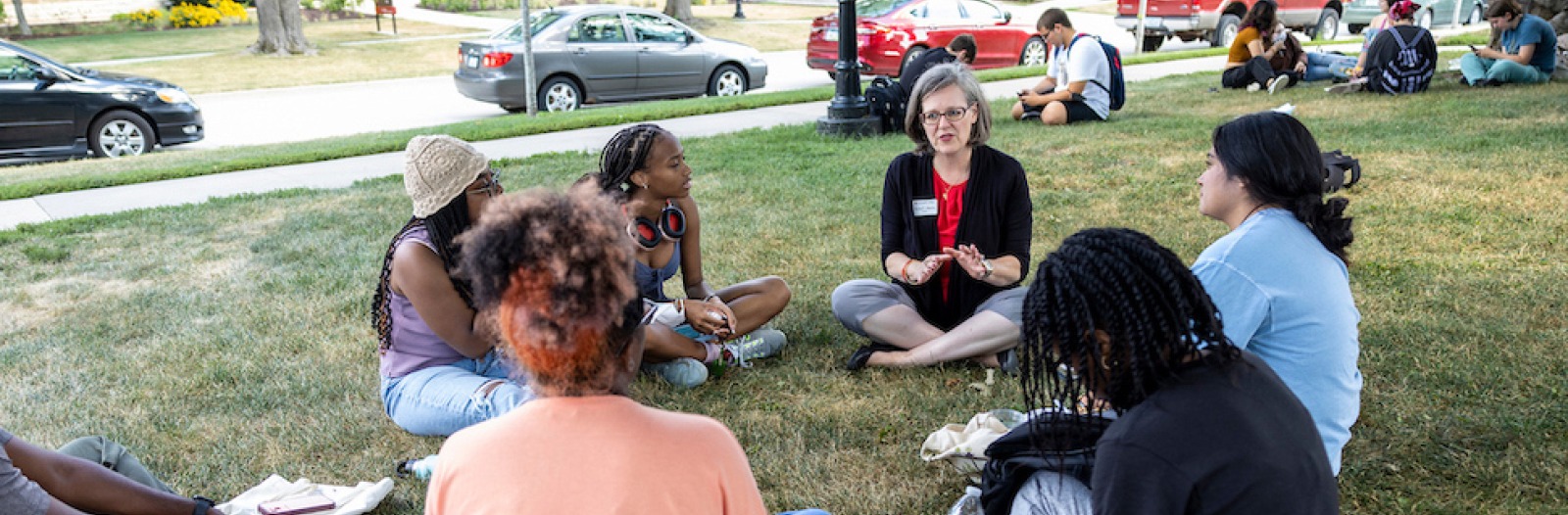 Grinnell President Anne Harris and Students Sit on a Lawn and Chat 