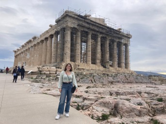 Kalea stands happily next to a Greek monument.