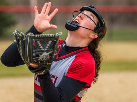 Softball player looking up, about to catch a ball