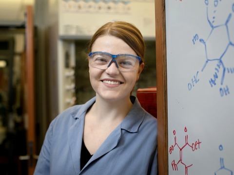 Jennifer Fulton wearing lab goggles standing by whiteboard