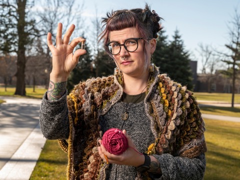 Senior Lecturer Jennifer Snook holds a ball of yard and a small vial of sand.