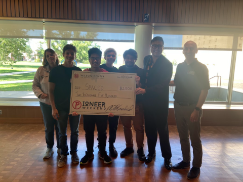 Pioneer Weekend's first-place team of five students with their oversized prize check. 