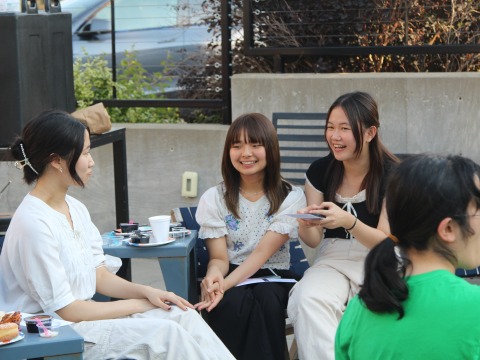 Three female Asian students smile as they talk.