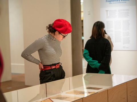 woman in red hat look down at art 