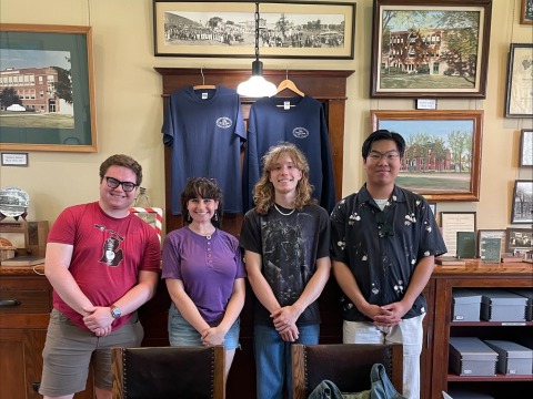 Four students pose in a small town historical museum surrounded by photos and artifacts