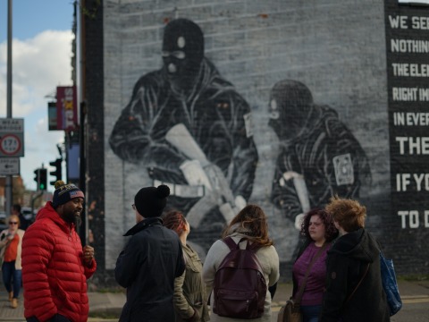 People gather and talk in front of a mural.