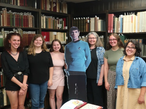 Four students and staff pose at the University of Iowa library.