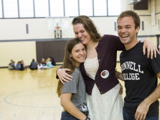 Three people with arms around each other smiling and laughing