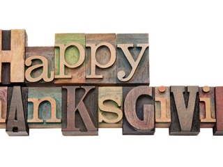 a series of wooden print blocks with letters of different sizes and colors spells out Happy Thanksgiving