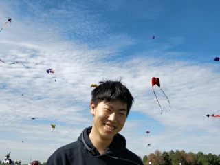Ryuta smiles in foreground with sky full of kites behind