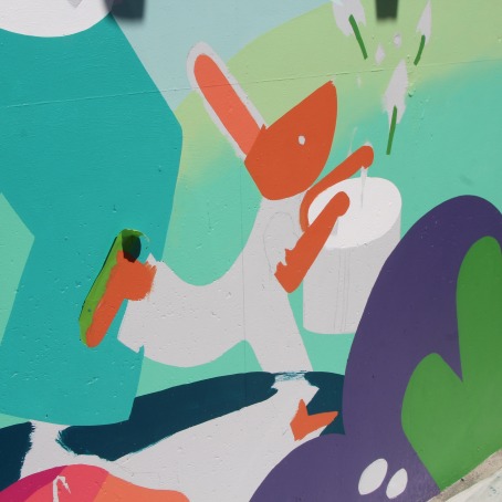 A mural wall with blue colors. In the center, a half-painted rabbit playing a drum.