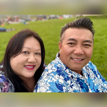 A Hmong man in a blue hawaiin shirt and his wife.