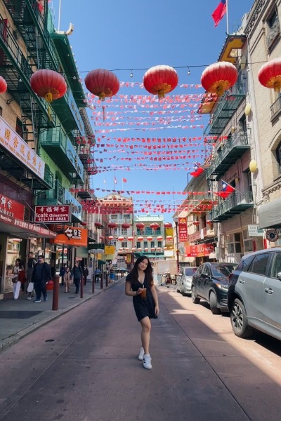 Alyson poses on a street in Chinatown decorated with flags and balloons