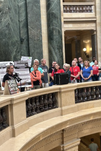 A group of people listen to a speaker in the capitol rotunda