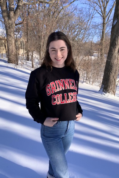 Hannah poses in the snow in her Grinnell sweatshirt