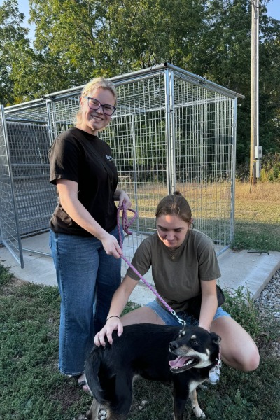 Two students with a dog on a leash